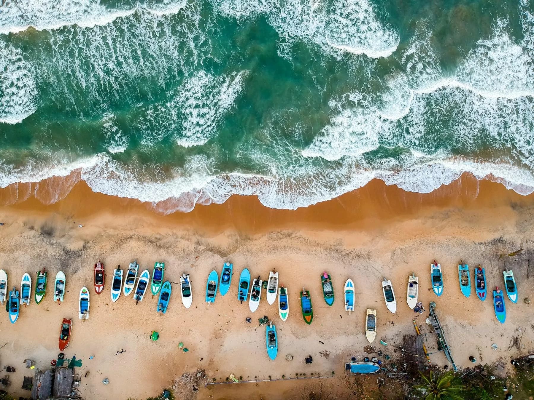 Bunte Fischerboote am Strand von Arugam Bay, aus der Luft gesehen