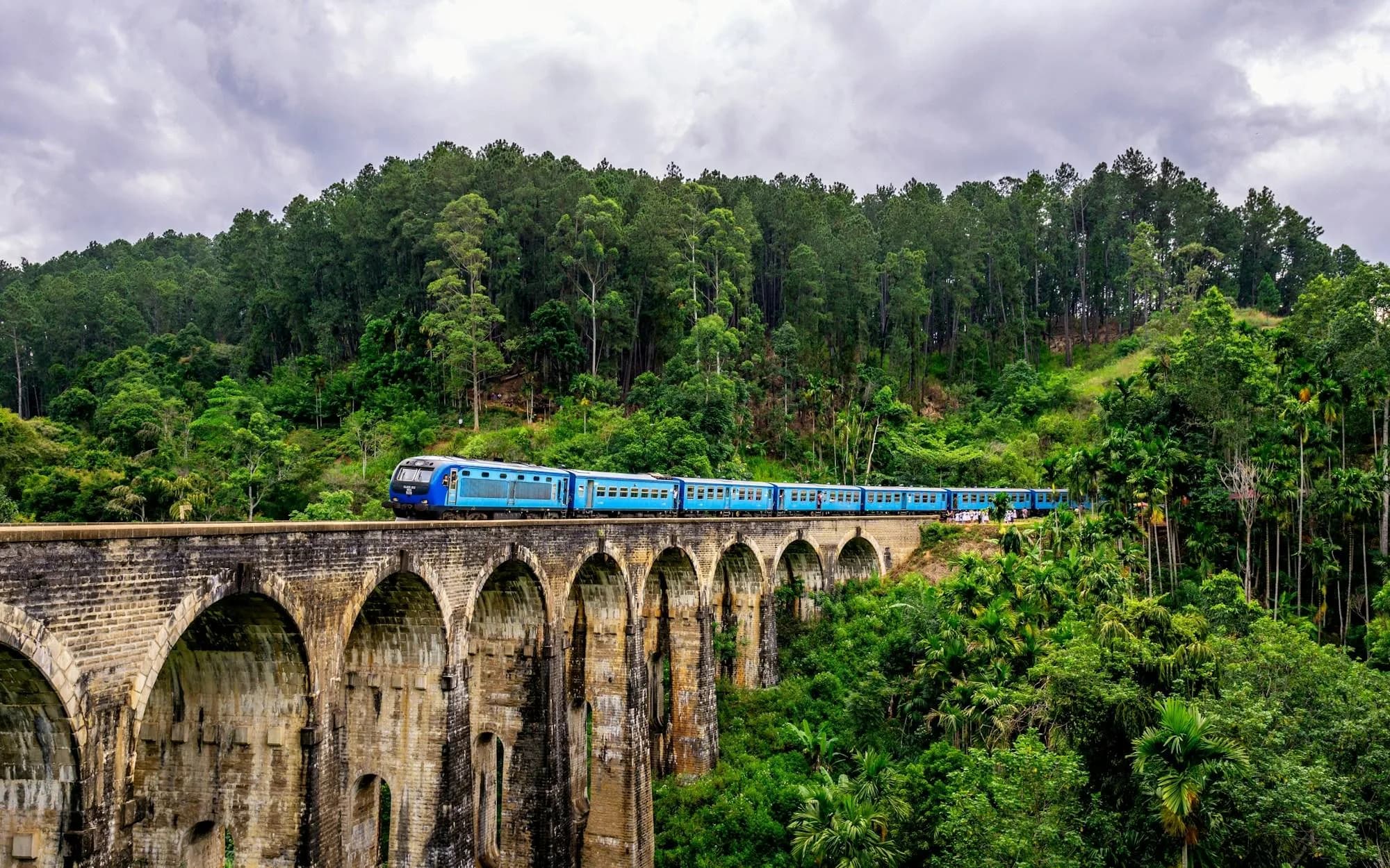 Blauer Zug auf der Nine Arches Bridge im Hochland Sri Lankas