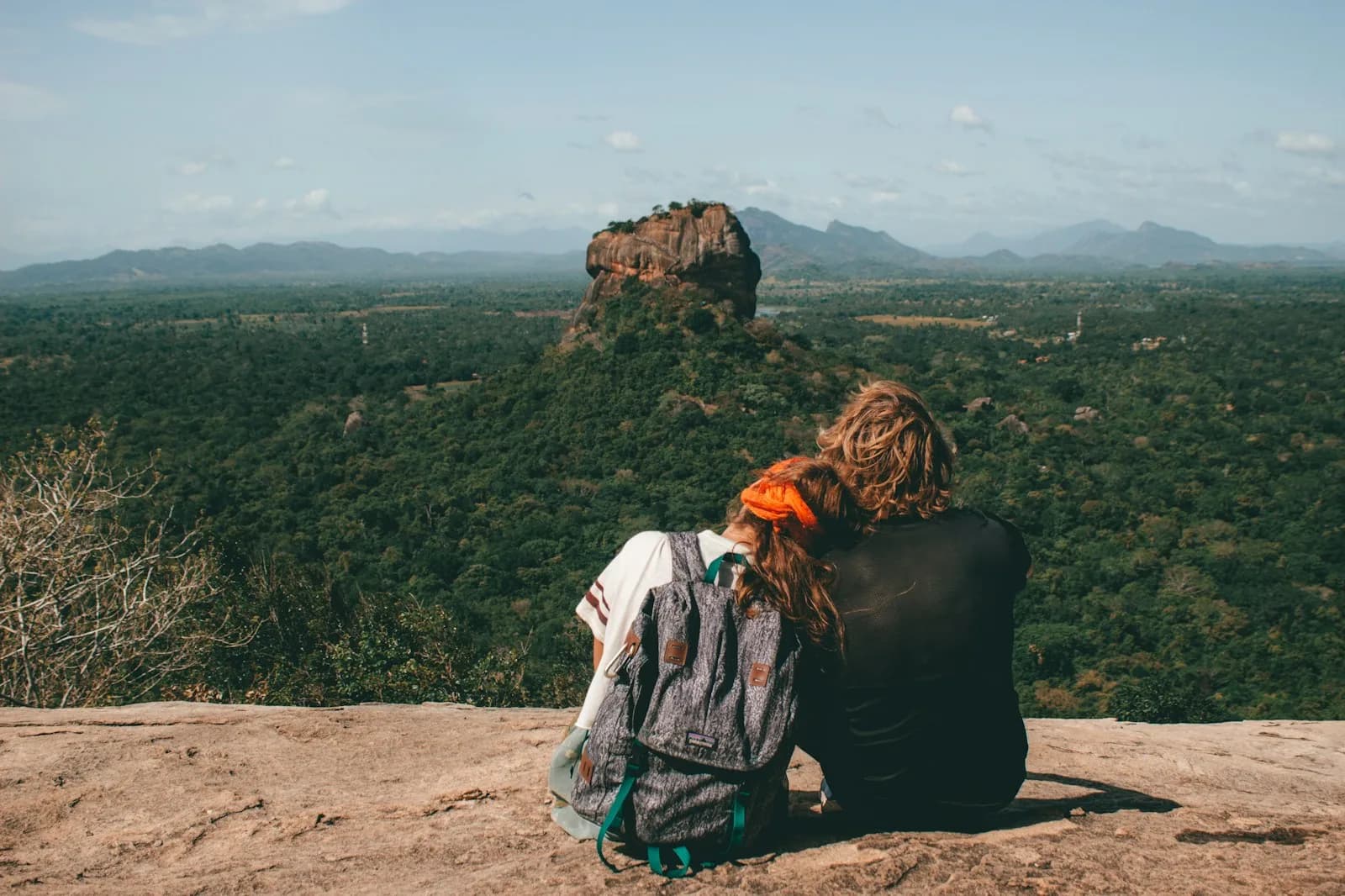 Ein Paar sitzt eng beieinander auf einem Felsen und blickt auf den Löwenfelsen von Sigiriya