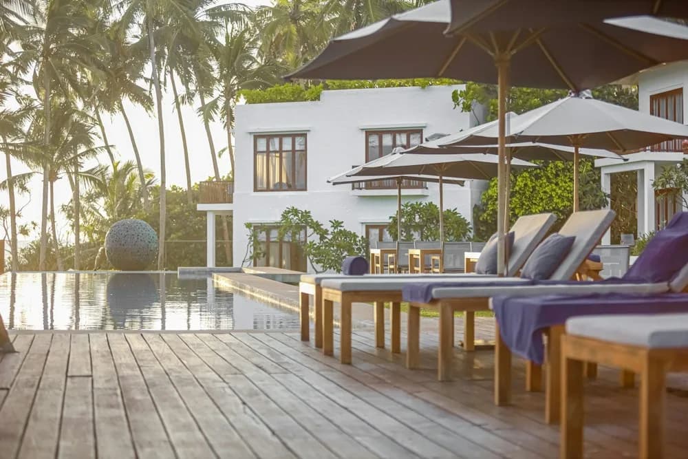 Poolterrasse mit Liegen und Palmen in einem Boutique-Hotel