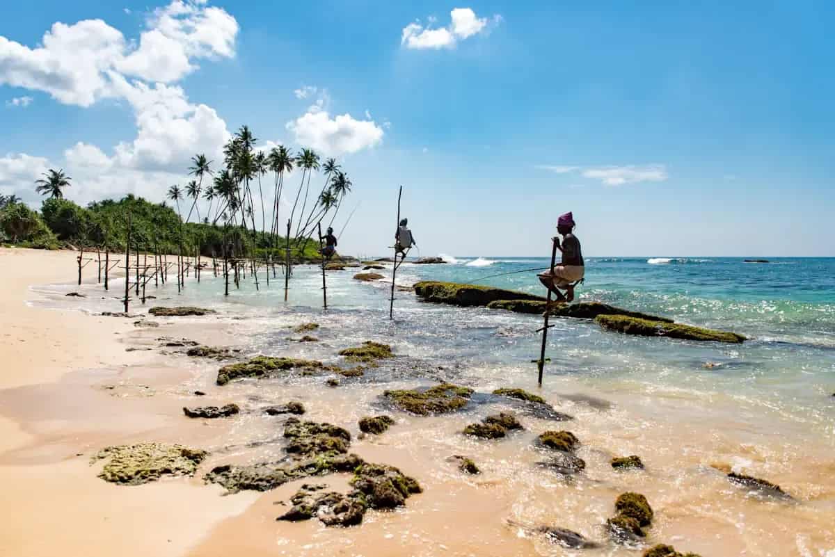 Stelzenfischer im flachen Meer bei Koggala